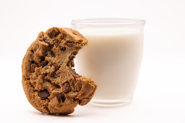 Cookie aux pépites de chocolat qui a été croqué, posé sur un verre de lait, sur fond  blanc