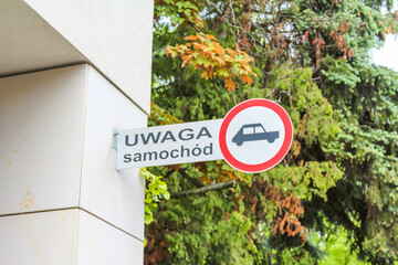 No Vehicles Warning Sign on Building Wall with Green Trees and Polish Text