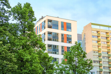 Modern Apartment Building with Distinctive Orange Accents Surrounded by Lush Green Trees