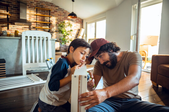 Father and son assembling furniture in their new home after moving in