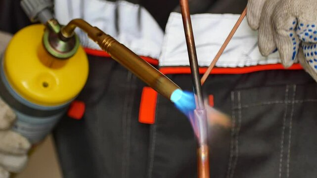 worker solders copper pipes with mapp gas