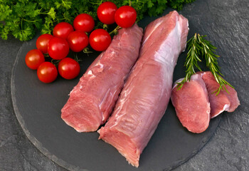 Raw pork loin decorated with tomatoes and parsley.