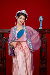 Beautiful woman wearing Chinese Ming Dynasty Hanfu with hairpin and flower ornaments on red...