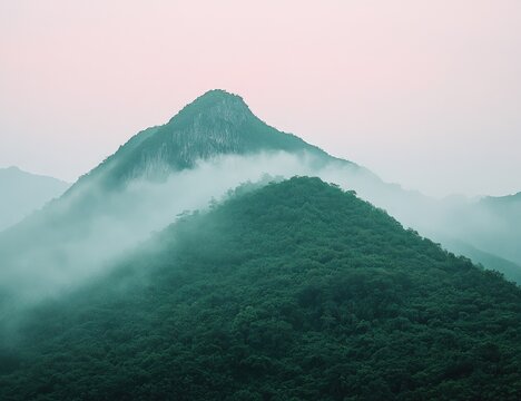 Misty mountain peaks emerge from a hazy, green landscape