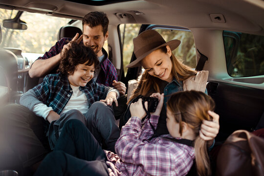 Happy family sitting in car taking pictures during road trip