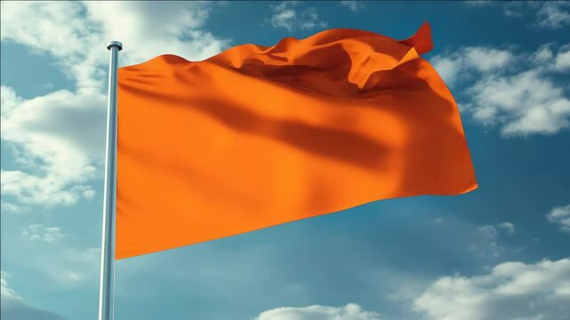 A large orange flag is blowing in the wind on a clear blue sky. The flag is on a pole and is the color orange