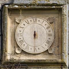 A STONE-SCULPTED TOWER CLOCK MISSING ITS HANDS