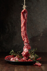 Dry-cured sausages with thyme and garlic on an old wooden table.