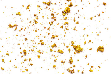 Close-up of scattered gold glitter flakes  on a white background. Soft focus enhances the beauty,...