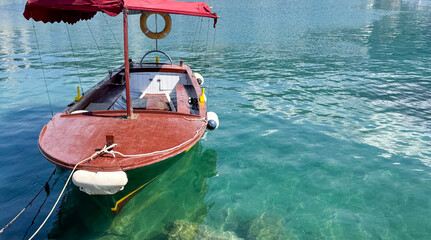 Obraz premium Wooden boat floating on clear turquoise water with reflections and serene surroundings