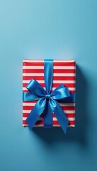Obraz premium Red striped gift box, blue bow, blue-gray background Top view , background, style