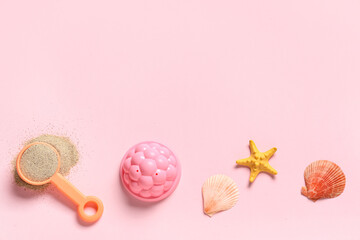 Beach toy, starfish, seashells and sand on pink background