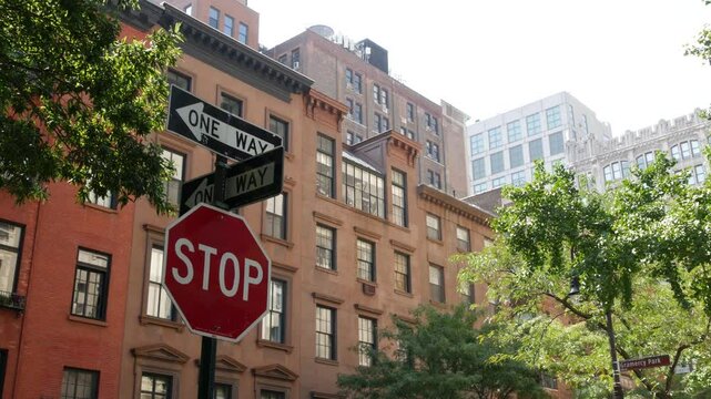 New York City oneway crossroad, Stuyvesant street intersection one way arrow. Manhattan Midtown residential building architecture, United States real estate. Red brick house wall, red stop road sign.