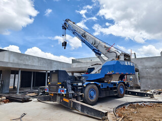 Obraz premium A large auto crane is parked right in front of a building that is currently under construction