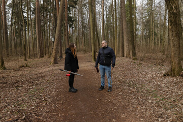 Fototapeta premium Two people on a tranquil nature walk, exploring a winding path lined with bare trees and forest undergrowth, dressed warmly for the chilly air in dark coats and boots.