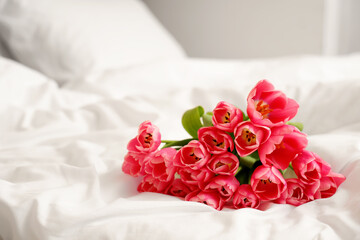 Bouquet of beautiful tulip flowers on cozy bed, closeup