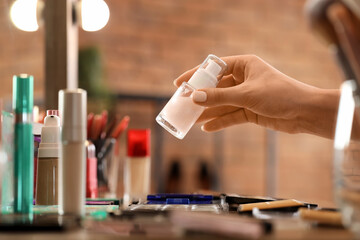 Professional makeup artist's hand with liquid highlighter in studio, closeup