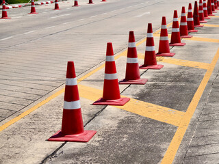A row of red and white traffic cones is placed by a road