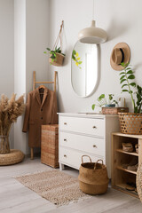 Interior of stylish hallway with mirror, coat and wicker baskets