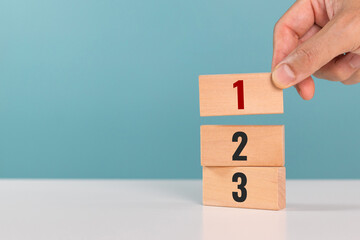 Concept of task priority and management. Priority of activities. A man hand place wooden cubes with number one, two and three