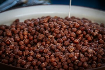 A detailed view of a bowl filled with dried brown peas, showcasing their rough texture and earthy color tones, ideal for natural food and agriculture visuals.