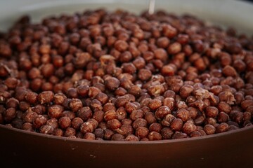 A detailed view of a bowl filled with dried brown peas, showcasing their rough texture and earthy color tones, ideal for natural food and agriculture visuals.