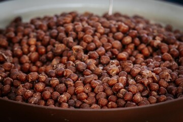 A detailed view of a bowl filled with dried brown peas, showcasing their rough texture and earthy color tones, ideal for natural food and agriculture visuals.