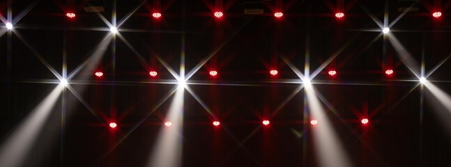 A row of red LED stage lights with a single bright green spotlight cutting through the darkness....