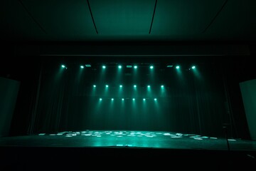 A dimly lit stage bathed in green lighting, with sheets of paper scattered across the floor....