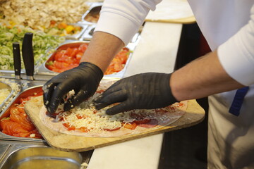 Els&auml;sser Flammkuchen wird belegt mit Handschuhen