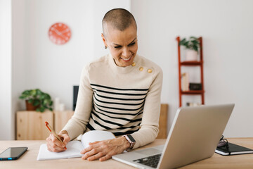 Mid adult businesswoman working on laptop computer at home office. Business and technology lifestyle concept.