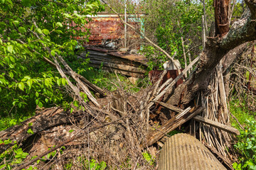 Fototapeta premium Junk in a village yard - a pile of branches and wooden planks. Abandoned place in the countryside, summer sunny day