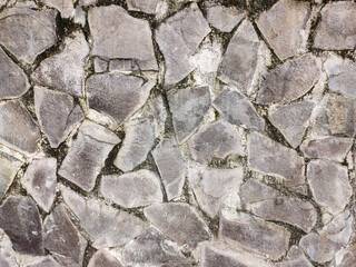 Rough stone wall texture, featuring irregularly shaped, gray rocks with visible mortar or gaps. The weathered surface creates a rugged and aged appearance, suggesting durability, natural construction