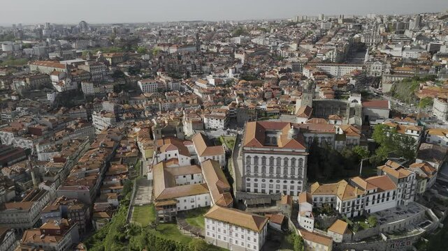 Drone hovers in place facing the Episcopal Palace and rotates to the left to face the Douro River in teh late afternoon in Porto, Portugal