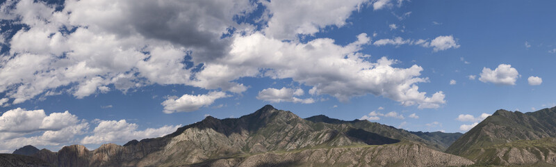 landscape with stone mountains peacks under white clouds