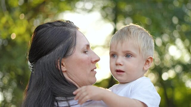 Mother plays with son nature. loving mother holding son outdoors. Joyful mother and son bonding during playtime in nature. Tender moment between mother and son playing. Playful interaction in nature.