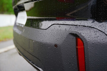 raindrops on car bumper highlight texture and durability of modern automotive design. close-up...
