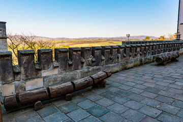 Historic stone terrace with wooden cannons overlooking scenic countryside