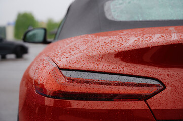 red sports car detail with raindrops highlights sleek design and modern aesthetics. captivating...