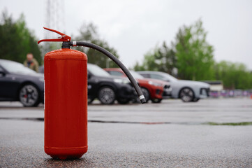fire extinguisher on wet asphalt with blurred cars in background, showcasing emergency preparedness...