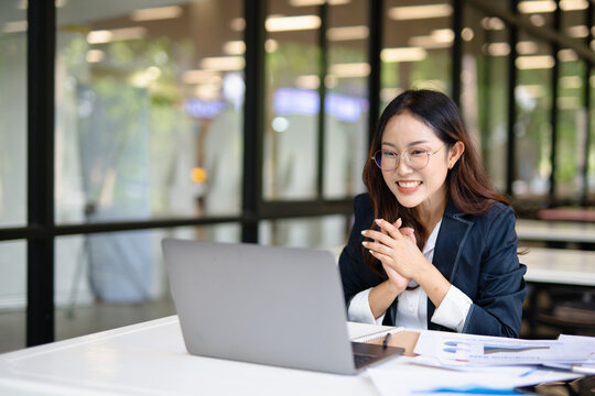  A young Asian woman is happy and excited after talking about her successful project and working ideas in the office.