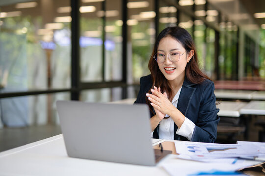 Asian woman laughing while talking on the phone in the office