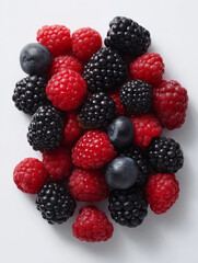 Flat lay of mixed berries arranged by color gradient (blackberry to raspberry) on white background.