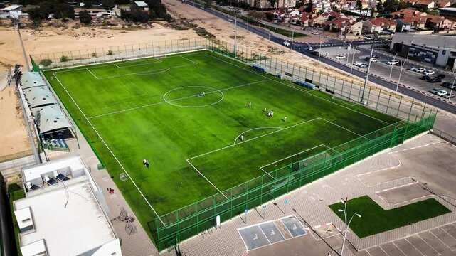 Drone view of a full-size outdoor soccer field with players practicing on synthetic grass - Powered by Adobe