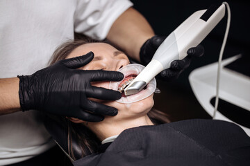 Conceptual dental technology, 3D scanning. A dentist performs a 3D scan of the oral cavity using an intraoral scanner in a modern dental clinic.