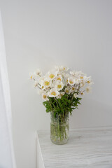bouquet of wild flowers in a vase stands on a light table and a white background. Nature in the house