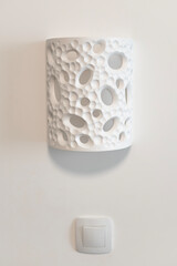 white sconce on a white wall above a switch