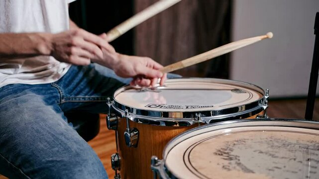 Close-up of a drumstick poised above a drum, captured from a side angle, emphasizing rhythm and motion, ideal for a music video theme.