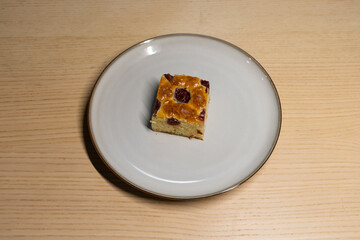 A slice of white chocolate brownie with cherries on top.