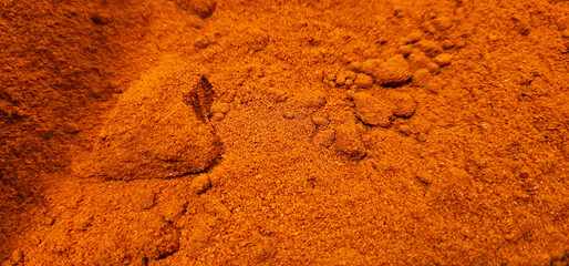 A close-up view of vibrant orange-brown powder with a fine, slightly clumped texture, filling the...